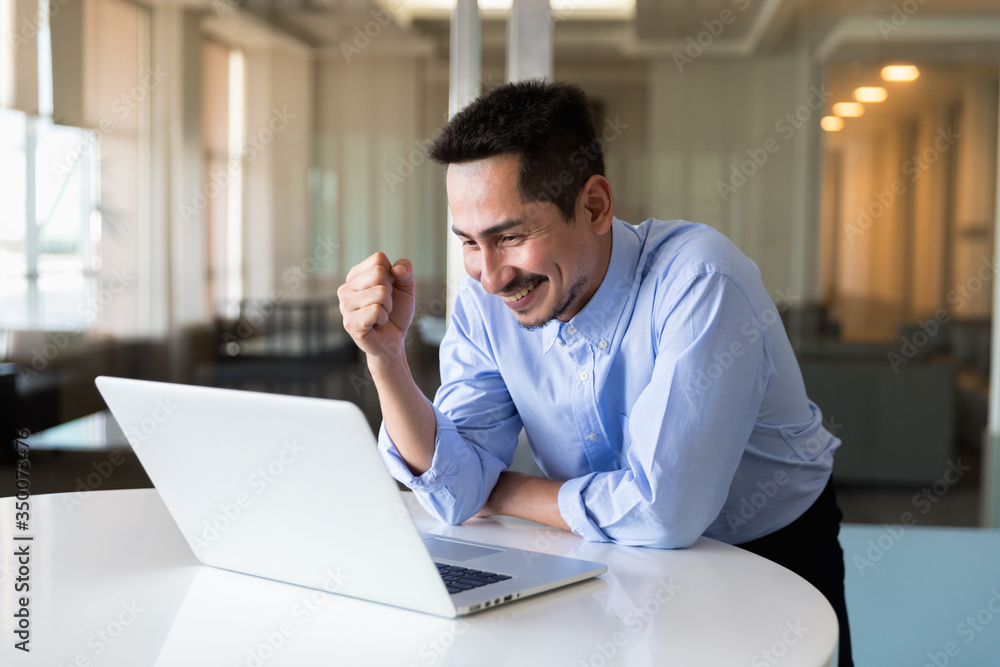 A young businessman using laptop standing working with happy in modern office, Concept stock up A young businessman using laptop standing working with happy in modern office, Concept stock up