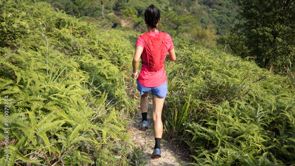 Woman trail runner running up on mountain slope in tropical forest Woman trail runner running up on mountain slope in tropical forest