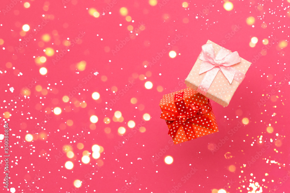 Obraz premium Two gift boxes on a bright pink background with gold bokeh lights