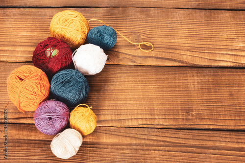 group of multi-colored woolen clews on a wooden background.