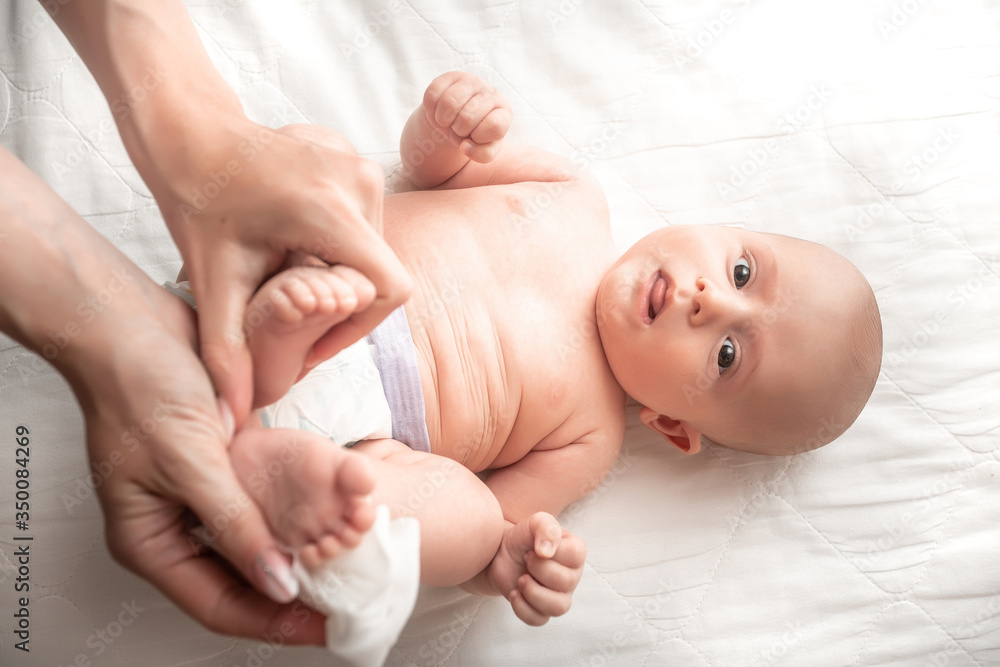 Newborn baby getting a diaper change: mom wiping baby's bottom with baby wipe. emotions of newborn baby. Concept Hygiene cleaning wipe, pure, clean Newborn baby getting a diaper change: mom wiping baby's bottom with baby wipe. emotions of newborn baby. Concept Hygiene cleaning wipe, pure, clean