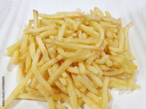 Homemade, baked french fries with herbs, salt and hot pepper made from an air fryer put on a white plate. The potato chips are a delicious and popular dish. Close up hot fast food.
