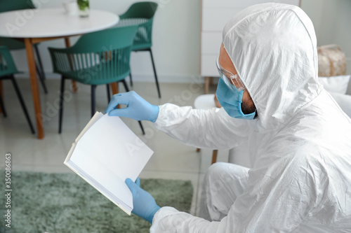 Man in biohazard suit reading book at home