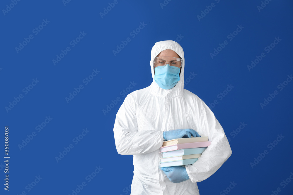 Man in biohazard suit and with books on color background Man in biohazard suit and with books on color background