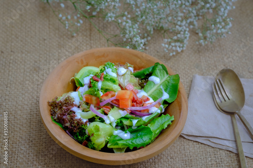Fresh salad bowl on brown cloth background, vegetable eating, diet food
