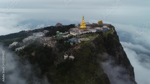 Time lapse of golden buddha statue at  Jinding Emei mountain Sichuan China  with sea of clouds flowing by the cliff UNESCO World Heritage site time-lapse aerial footage photo