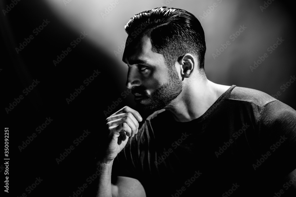 Monochrome portrait of young man with beard thinking about problem
