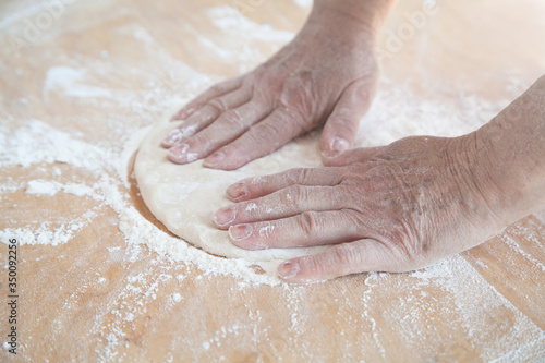 Making dough by female hands on wooden table.