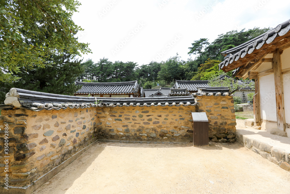 Traditional Korean house roof behind the stone wall. Dosanseowon, Andong, Gyeongsangbuk-do Traditional Korean house roof behind the stone wall. Dosanseowon, Andong, Gyeongsangbuk-do