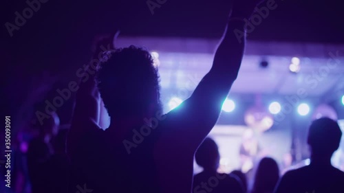 Back view of a man making the sign of the horns mano cornuta sign at a rock metal concert of a small outdoor festival. photo