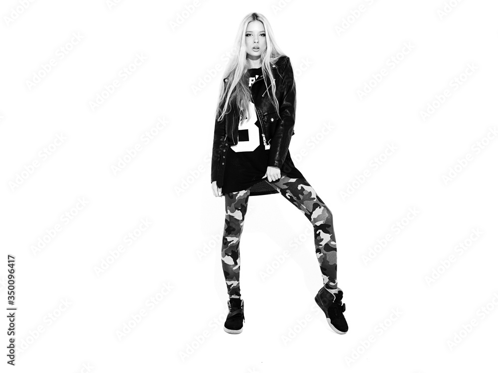 Young beautiful hipster bad girl in black leather jacket and stylish fashionable tight military pants leggings.Model with earring in nose.Sexy carefree woman posing in studio.Isolated on white Young beautiful hipster bad girl in black leather jacket and stylish fashionable tight military pants leggings.Model with earring in nose.Sexy carefree woman posing in studio.Isolated on white