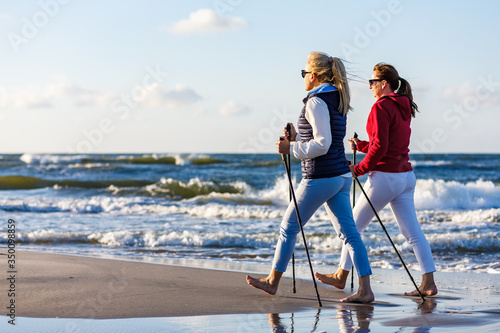 Платно Nordic walking - two women working out on beach