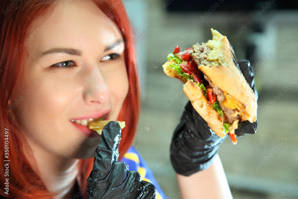 Girl with a juicy burger. Beautiful happy young woman with tasty burger on light background. Girl holds juicy cheeseburger.