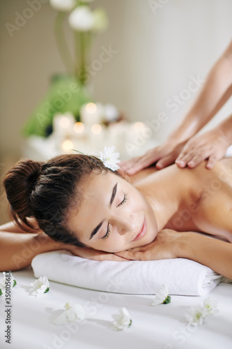 Beautiful young woman getting professional back massage in spa salon with moisturizing oils