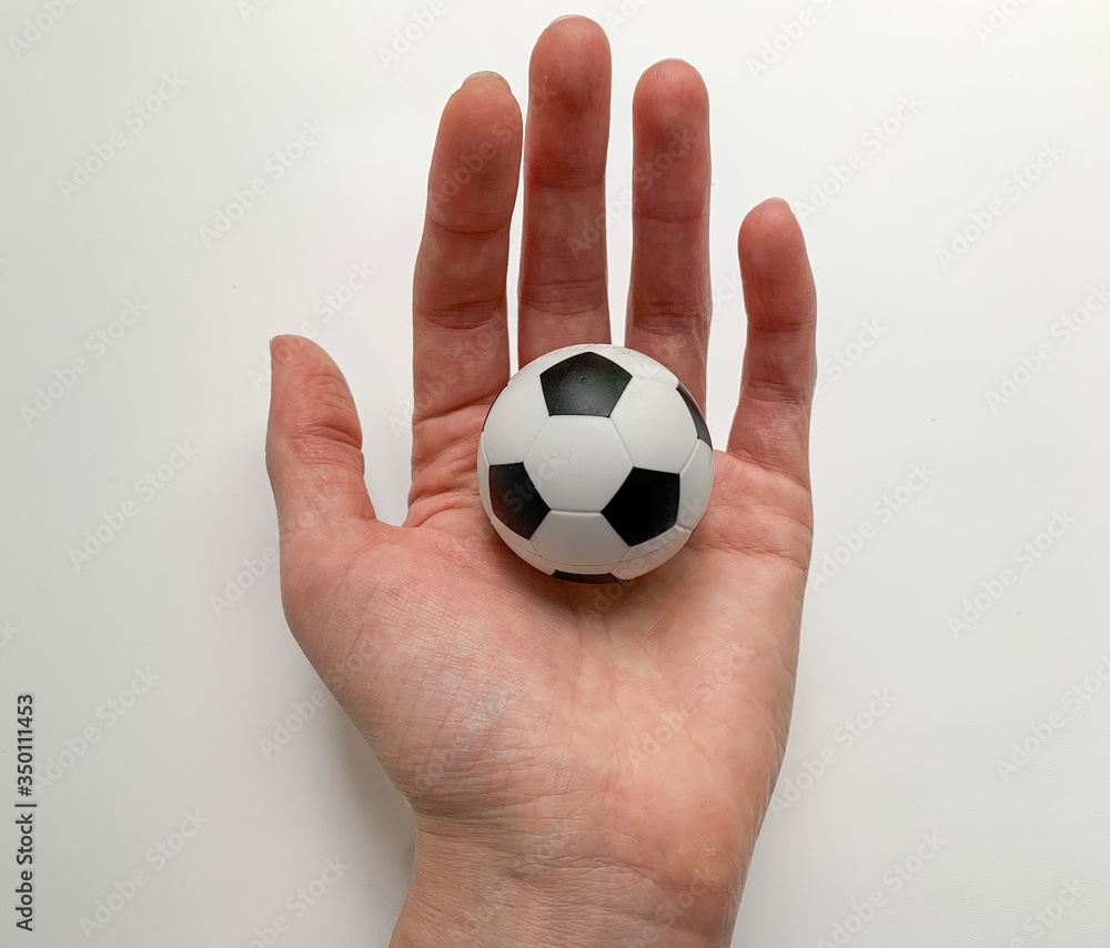 Fototapeta premium A small soccer ball in the hand of a girl on a white background.