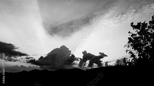 Vintage image of black light of the sun on mountains, while gray clouds appear like an imaginary dog ​​top a mountain that appears above, evening landscape trees in countryside, Thailand.