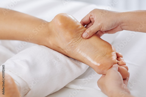 Close-up image of woman getting relaxing feet massage with oils in spa salon
