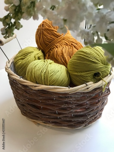 Balls of yarn in a basket and on a white background. Lilac. The view from the side