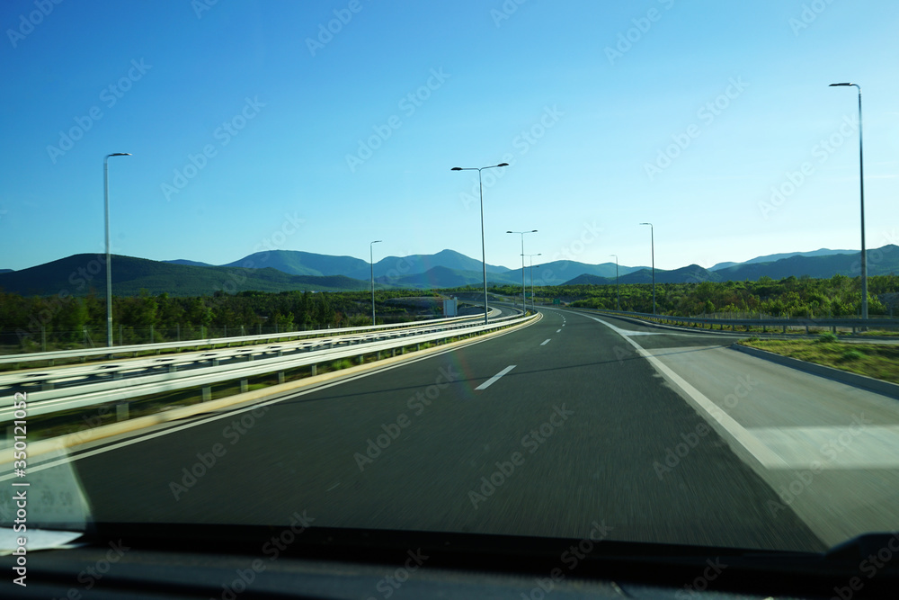 Beautiful roadside landscape scenery with mountain range and clear blue sky view from front car windshield