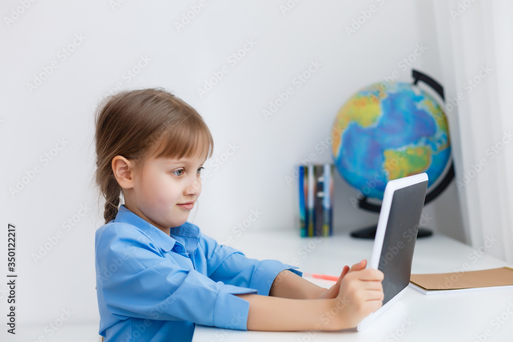 Smart little schoolgirl with digital tablet in a classroom. Child in an elementary school. Education and learning for kids. Smart little schoolgirl with digital tablet in a classroom. Child in an elementary school. Education and learning for kids.