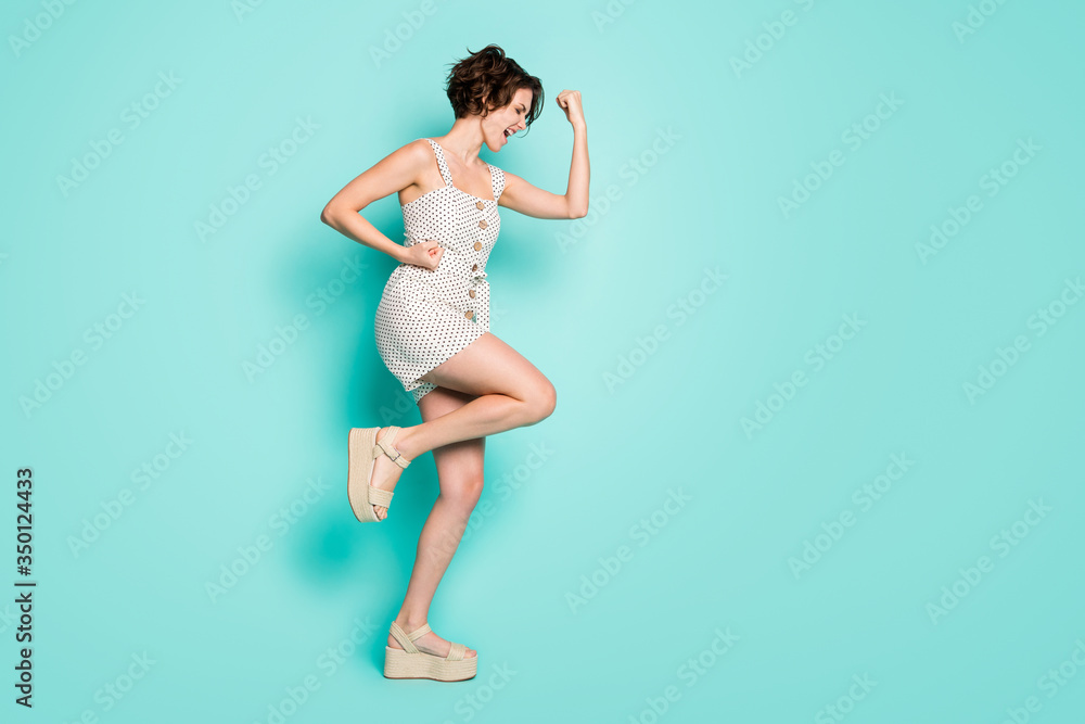 Full size profile photo of cool cheerful lady raise fists hands celebrate lottery winning wear casual summer dotted overall open toe shoes isolated pastel teal color background