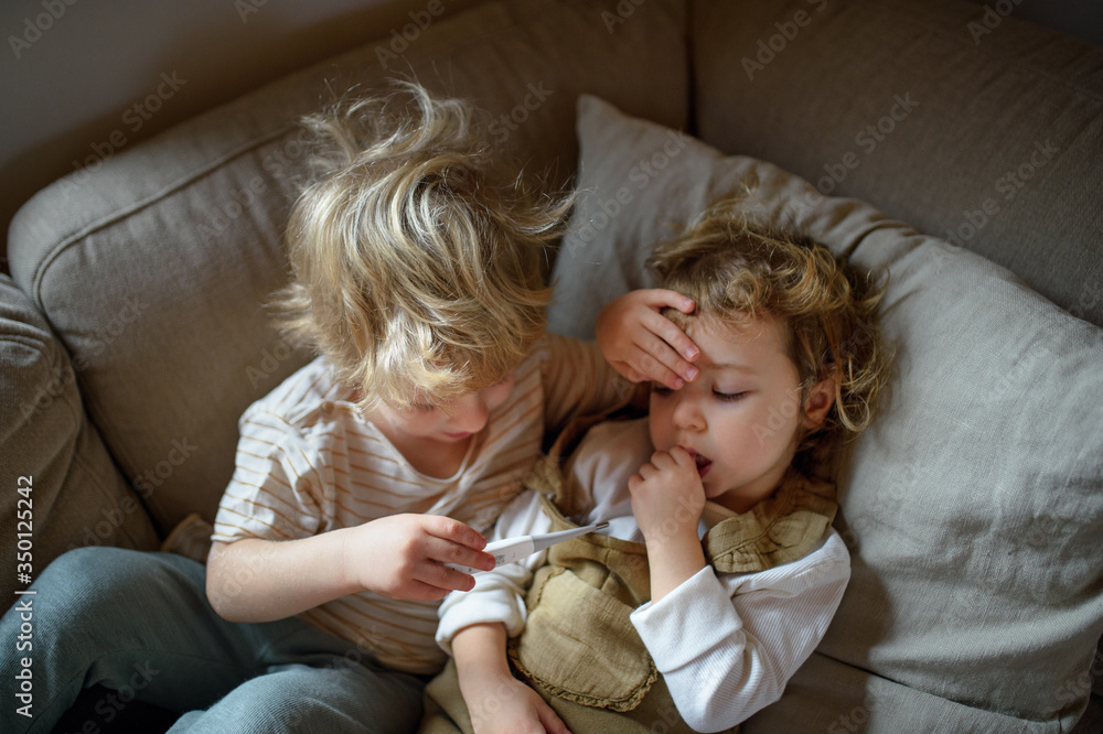 Two small sick children brother and sister at home lying in bed. - obrazy, fototapety, plakaty 