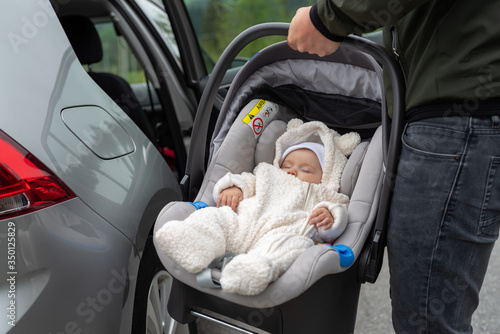 Father carries newborn daughter in car seat being put in car