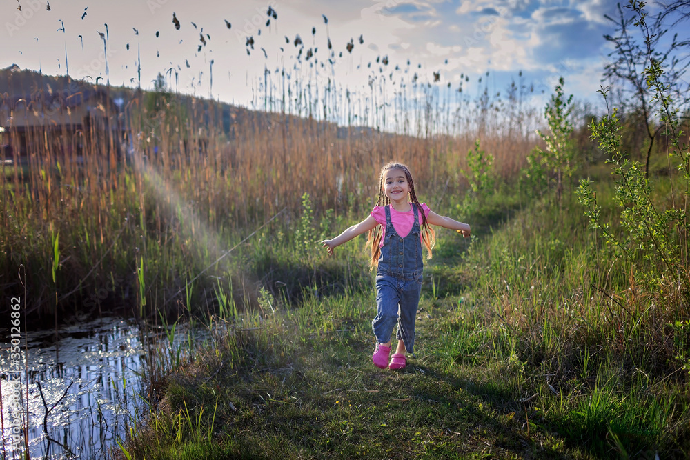 Cute little girl running through a beautiful meadow near the lake, lifestyle after lockdown Cute little girl running through a beautiful meadow near the lake, lifestyle after lockdown