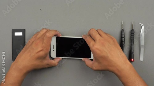 Speed up (time lapse) and top table view (high angle) of technician or engineer using tools for repairing or replace new screen of broken and damaged smartphone on desk. 4K resolution ultra HD