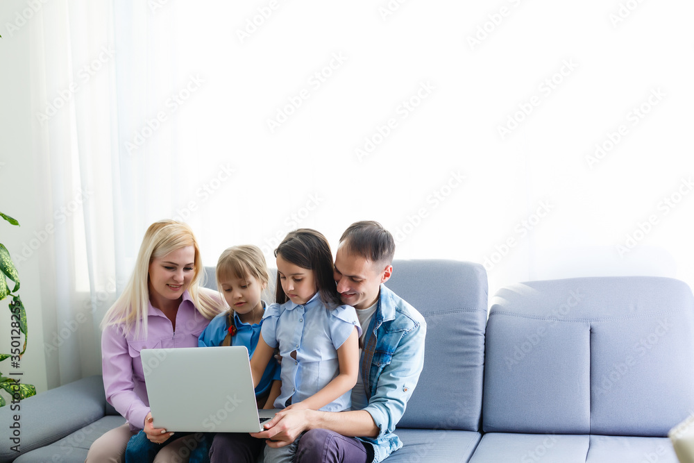 Happy family of four parents and cute little kids children enjoy using the tablet, watching cartoons, make internet video call or shopping online looking at computer screen sit together at home Happy family of four parents and cute little kids children enjoy using the tablet, watching cartoons, make internet video call or shopping online looking at computer screen sit together at home