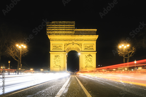 Beautiful cityscape urban street view of the Arc de Triomphe in Paris, France, on a spring evening after sunset at night, seen from the Champs-Elysees with traffic © dennisvdwater