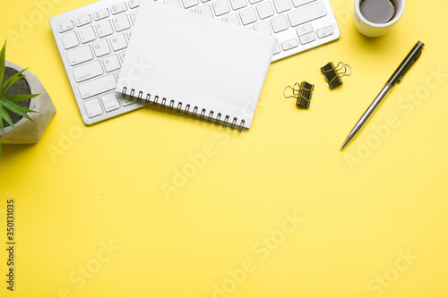 Yellow desk office with laptop, smartphone and other work supplies with cup of coffee. Top view with copy space for input the text. Designer workspace on desk table essential elements on flat lay