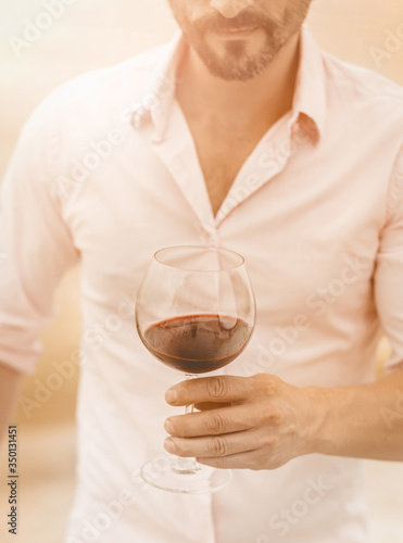 Bearded man holds a glass of red wine