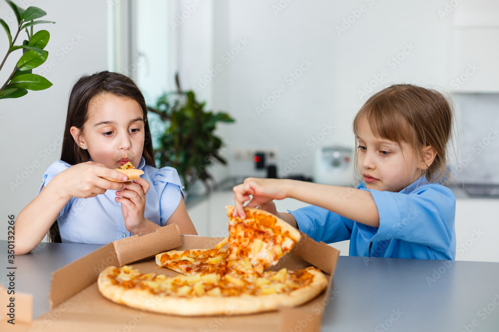 Two smiling girls eat pizza slices at home Two smiling girls eat pizza slices at home