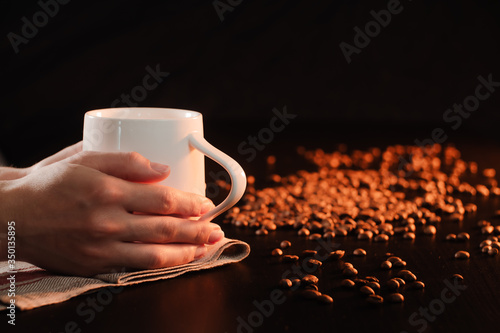 Closeup female hands holding a coffee cup with freshly brewed coffee.