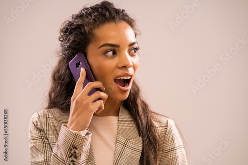 Studio shot portrait of beautiful african-american ethnicity businesswoman talking on phone.