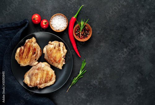 Skinless grilled chicken thighs with spices on a stone background with copy space for your text