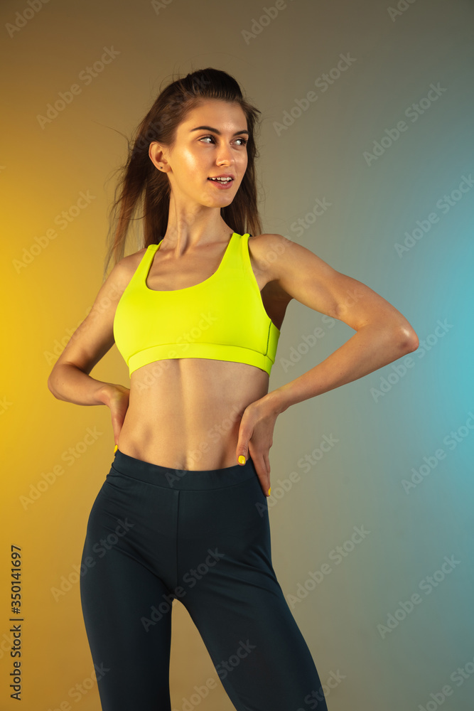 Fashion portrait of young fit and sportive caucasian woman on gradient background. Fit sportswoman posing, looks confident. Perfect body ready for summertime. Beauty, resort, sport concept. Fashion portrait of young fit and sportive caucasian woman on gradient background. Fit sportswoman posing, looks confident. Perfect body ready for summertime. Beauty, resort, sport concept.
