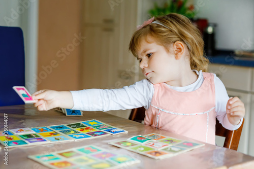 Adorable cute toddler girl playing picture card game. Happy healthy child training memory, thinking. Creative indoors leisure and education of kid during pandemic coronavirus covid quarantine disease