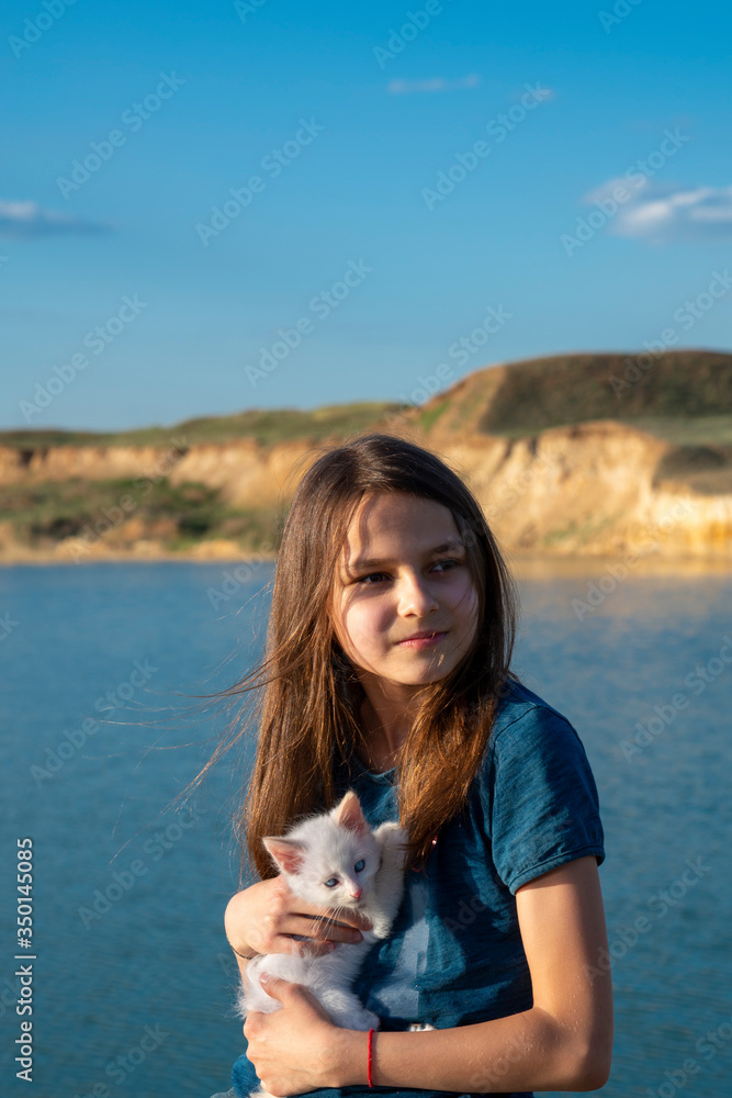 Beautiful girl on the lake with a white kitten in her hands. Beautiful girl on the lake with a white kitten in her hands.