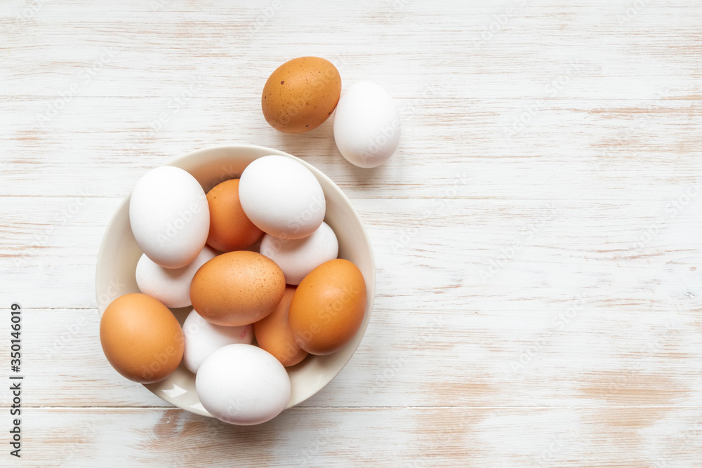 Free-range organic brown and white eggs in bowl on wood background with copy space