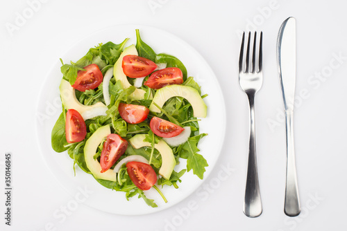Healthy diet concept. Top above overhead close-up view photo of a salad plate with olive oil fork and knife aside isolated on white background