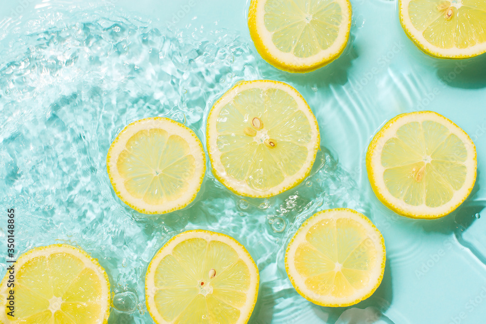 Slice of lemon underwater or in water with splashing and droplet top view flat lay on blue background Slice of lemon underwater or in water with splashing and droplet top view flat lay on blue background