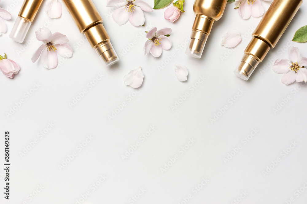Cosmetics springtime Concept. Cosmetics, spring white flowers green leaves on light background. Cosmetic mock up gold bottles. Flat lay top view copy space. Branding products, beauty background Cosmetics springtime Concept. Cosmetics, spring white flowers green leaves on light background. Cosmetic mock up gold bottles. Flat lay top view copy space. Branding products, beauty background