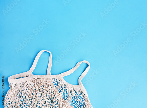 Cotton net bag on a blue background. Sustainable lifestyle. Eco friendly concept. Top view