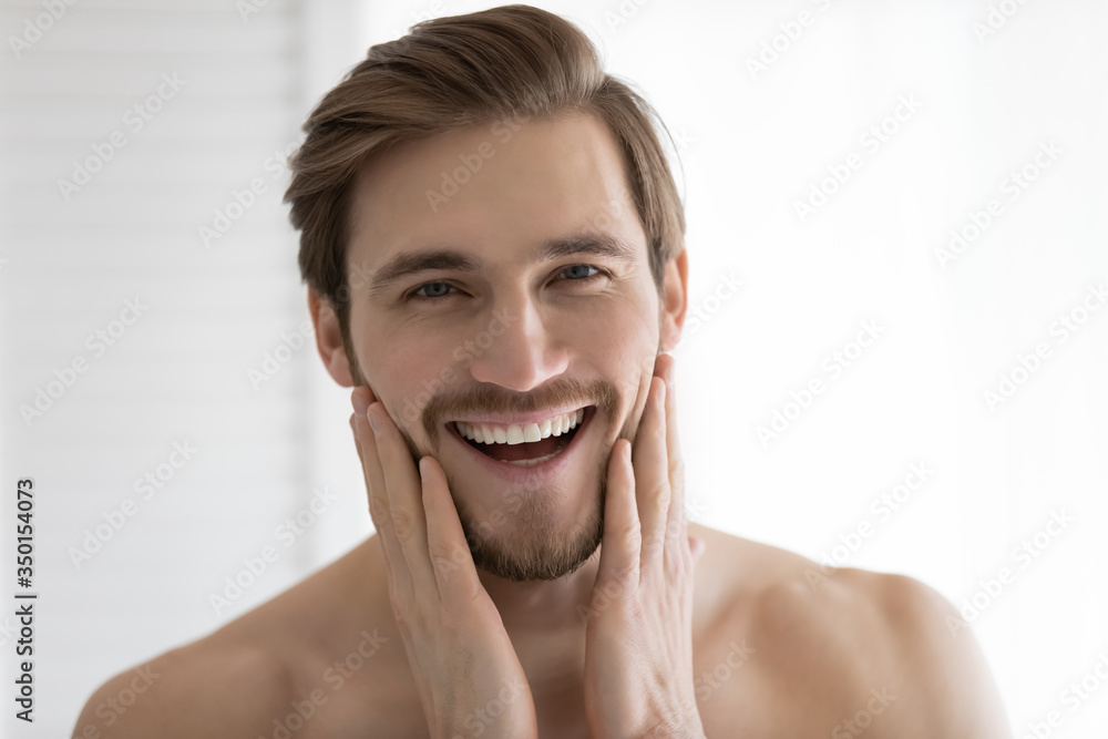 Close up headshot portrait of overjoyed young caucasian man touch healthy clean face after shaving, smiling millennial male satisfied with facial treatment, apply cream or balm, skincare concept Close up headshot portrait of overjoyed young caucasian man touch healthy clean face after shaving, smiling millennial male satisfied with facial treatment, apply cream or balm, skincare concept