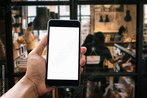 A woman hand holding smart phone device in the coffee shop or cafe background. 