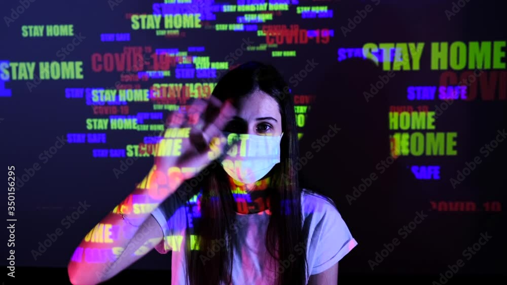 Caucasian woman waving hand look at camera. Young beautiful girl wears protective medical mask to protect the epidemic. Reflection projection text on display, on wall and body. Quarantine Covid-19. Caucasian woman waving hand look at camera. Young beautiful girl wears protective medical mask to protect the epidemic. Reflection projection text on display, on wall and body. Quarantine Covid-19.