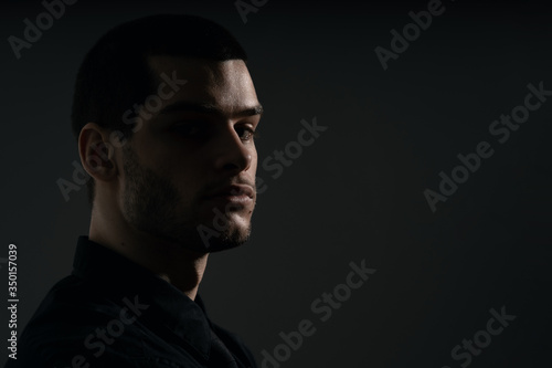 Low-key portrait of modern business person. Handsome businessman standing on dark background