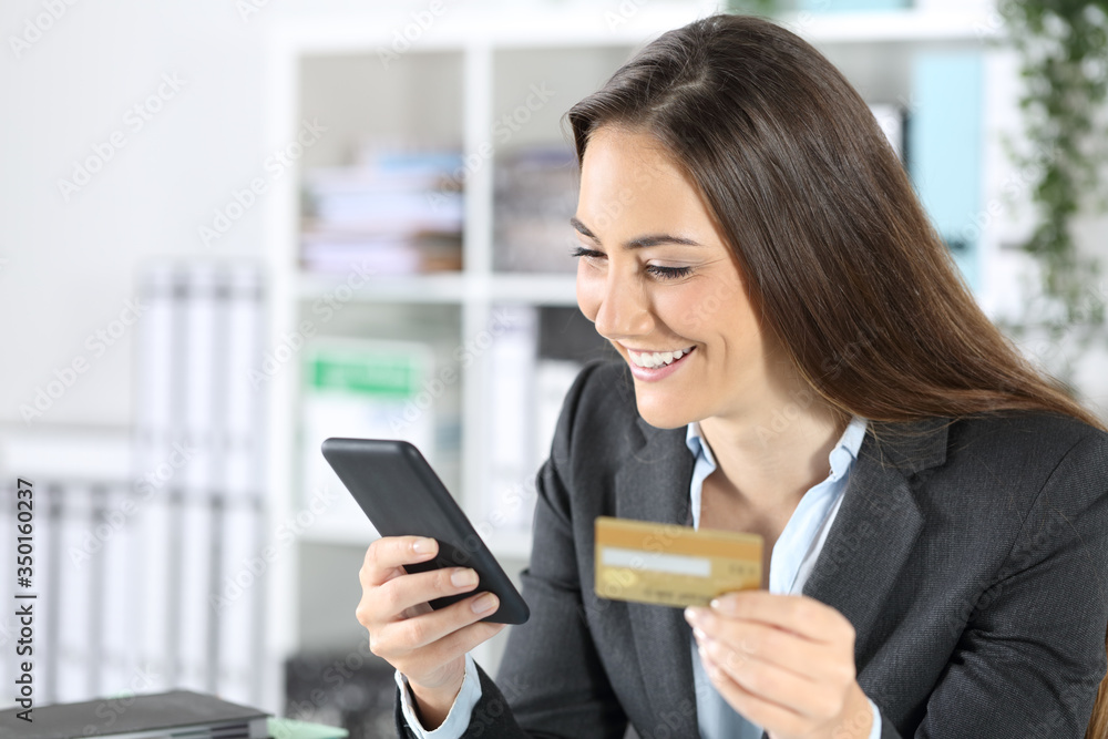 Happy executive paying with card on phone at office Happy executive paying with card on phone at office